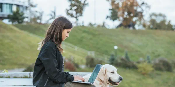 A Woman With A Laptop Computer And A Dog